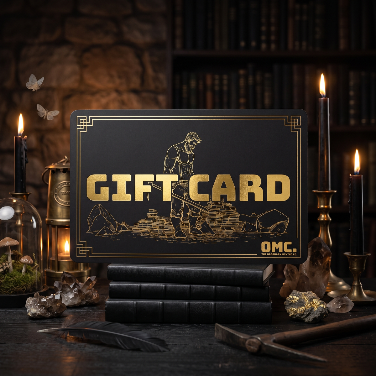 OMC gift card in black with gold foil miner artwork, standing in a dark candlelit study