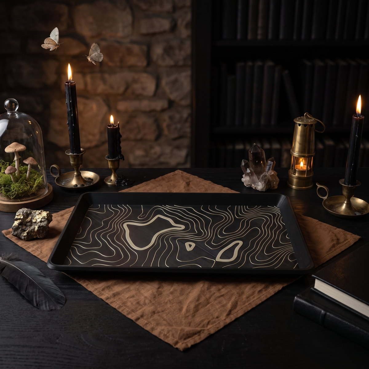 Topographic 3D-printed black tray with contour lines in a dark candlelit study